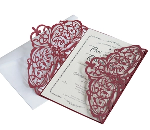 Detail of laser-cut burgundy floral invitation with white inner card and white envelope