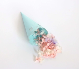 Detail of light blue laser-cut lace confetti cone filled with pastel hydrangea petals