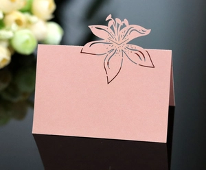 Macro detail of laser-cut lily flower pattern on elegant pink paper wedding place card