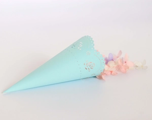 Macro shot of light blue laser-cut paper confetti cone with rose floral hollow pattern