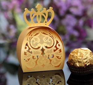 Macro shot of gold laser-cut crown favor box with intricate heart pattern and reflection