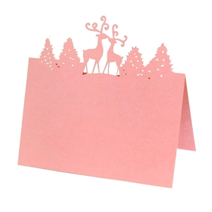 Detail of pink laser-cut place card showing reindeer and pine forest silhouettes