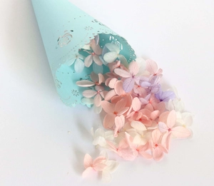 Macro view of colorful dried petals spilling from a laser-cut lace wedding paper cone