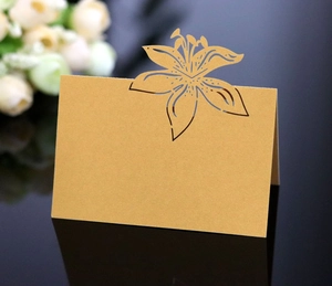 Macro detail of laser-cut lily floral pattern on a gold-brown card with elegant reflection