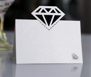 Macro detail of white pearlescent place card with laser-cut diamond design and shimmer