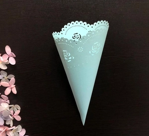 Detail of light blue lace paper cone with laser-cut rose patterns for wedding confetti