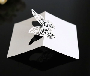 Detailed laser-cut white butterfly table card with 3D folding design for weddings