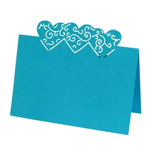 Detail view of light blue laser-cut heart place cards with elegant floral scroll patterns