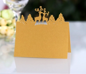 Detail of laser-cut reindeer and pine tree silhouette on pearlescent gold place card