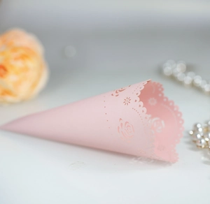Close-up of pink laser-cut paper cone with rose floral pattern for wedding confetti and petals