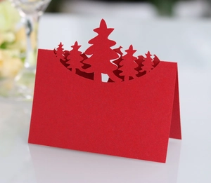 Detail of red 3D laser-cut Christmas tree table card with intricate hollow paper design