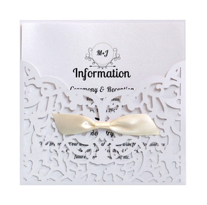 Elegant laser cut white wedding invitation cover with a silk beige bow and inner card