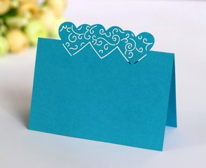Macro shot of laser-cut heart pattern on blue wedding place card in standing position