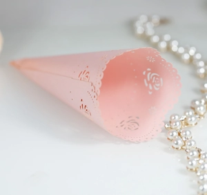 Detail of pink laser-cut lace paper cone with rose pattern for wedding confetti and petals
