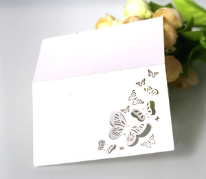 Detail of white laser-cut butterfly place card with elegant hollow pattern on pearl paper