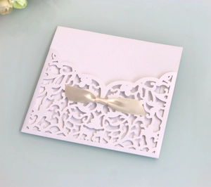 Detailed laser-cut lavender lace invitation cover with a soft golden satin ribbon bow