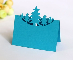 Detail of 3D laser-cut Christmas tree place card in blue paper with forest silhouette