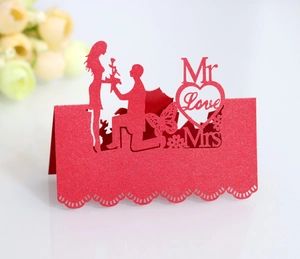 Detail of red glitter laser cut wedding place cards with Mr and Mrs heart silhouettes