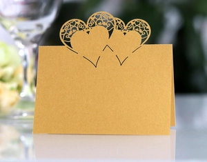 Detail of laser-cut heart pattern on gold pearlescent place card for wedding table