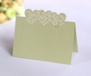 Close-up of sage green laser-cut heart place card with intricate hollow vine details