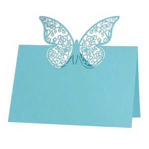 Detail of light blue laser-cut butterfly place card with intricate floral hollow patterns