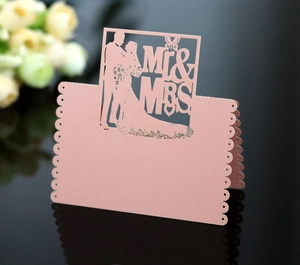Macro detail of laser-cut Mr & Mrs wedding place card with pink butterfly silhouette