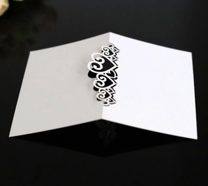 Detail of laser-cut heart pattern on a minimalist white card with black background reflection
