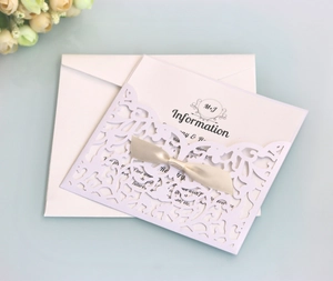 Detailed laser-cut white wedding invitation with elegant cream ribbon and custom card