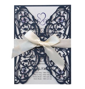 Laser-cut navy blue invitation card with butterfly pattern and cream satin bow detail