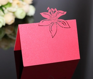 Detail of red glitter laser-cut table card with lily design on a mirrored surface
