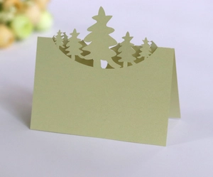 Detail of laser-cut pine tree design on a green Christmas table place card
