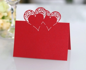 Detail of red hollow heart laser cut place card with intricate folding pattern