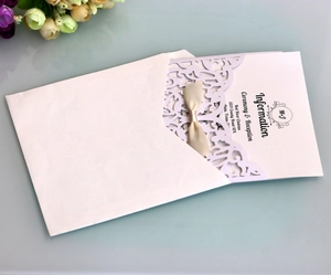 Macro shot of laser-cut lavender lace invitation with satin ribbon and floral details