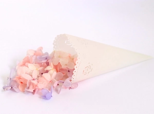 Macro detail of laser-cut white lace paper cone filled with soft pastel flower petals