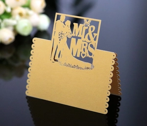 Macro shot of gold laser-cut Mr & Mrs wedding place card with butterfly and silhouette detail