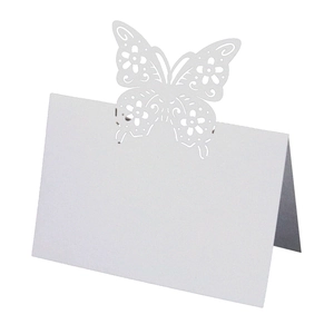 Detail view of white laser-cut butterfly place card with intricate floral hollow pattern