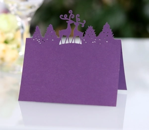Macro shot of laser-cut purple place card featuring a reindeer and forest silhouette
