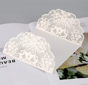 Detailed laser-cut hollow rose pattern on white invitation cover with scalloped edges