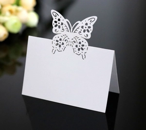 Detailed laser cut white butterfly place card with pearl paper texture on black surface