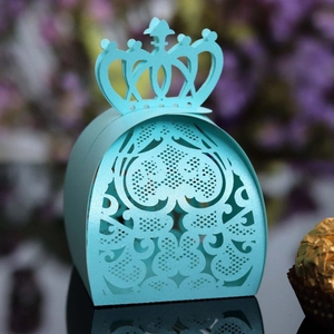 Macro shot of light blue laser-cut crown favor box with heart and floral hollow patterns