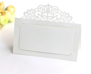 Detail of laser-cut white lace place card with floral patterns for weddings and events