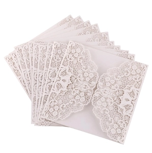 Detail of laser-cut off-white wedding invitation covers with intricate lace floral patterns