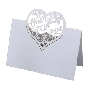 Detail of laser-cut 'One Love' heart pattern on white folding wedding place card
