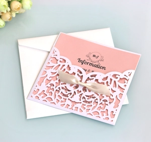 Detailed laser-cut wedding invitation set with champagne ribbon bow and pearl white shell