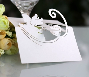 Macro detail of laser-cut white pearl paper place card with Cupid heart for weddings