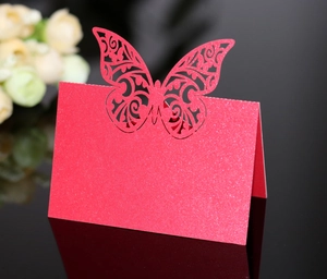 Macro shot of red glitter laser-cut butterfly place card for weddings on black surface