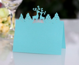 Detail of laser-cut reindeer and pine trees on light blue pearlescent tent card