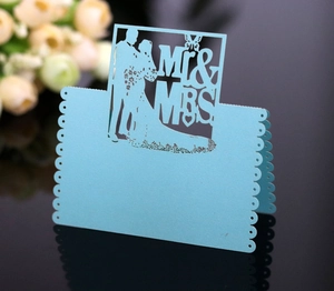 Close-up of laser-cut light blue pearl paper place card with Mr & Mrs wedding silhouette
