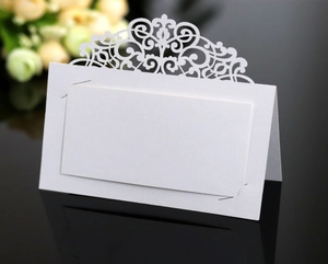 Macro shot of elegant white laser-cut wedding place card with intricate vine details