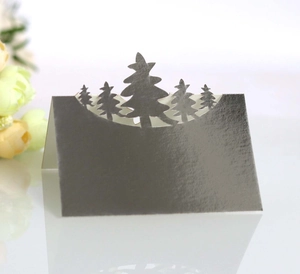 Laser-cut 3D grey paper place card featuring a silhouette of five Christmas pine trees